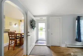 Entry to living room with hardwood floors and large windows.