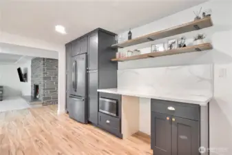 Modern trendy kitchen with stainless steel appliances and desk or wine frig area.