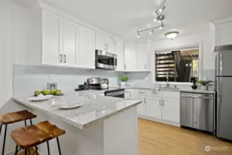 Fully equipped kitchen with stainless steel appliances + an eating bar area.
