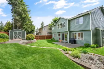 Large private backyard with lush green grass, patio, storage shed and backs to greenbelt.