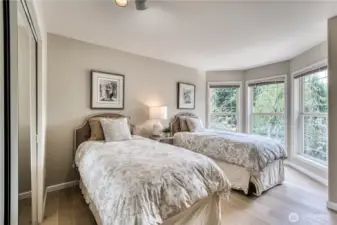 Bedroom #2 with hardwood flooring, mirrored closet doors and views of lush landscaping.