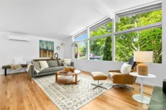 Spacious living room with newly refinished hardwood floors and large west-facing windows that frame the view of the lush surroundings and sunsets. Mid-century details like vaulted ceilings and exposed beams throughout.