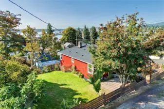 View of the home with fully fenced yard, garden area and water view.