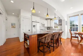 A view of the kitchen with the dining space in front of windows.
