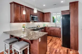 Lovely kirchen with rich stained cabinetry, stainless appliances, and granite countertops and peninsula seating.