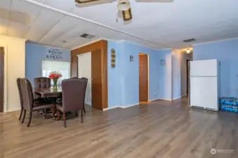 View from the kitchen into the open dining area, with the hallway leading to the primary suite, second bedroom, and main guest bath.