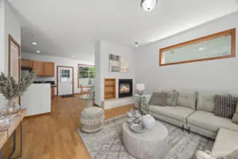 Looking across the living room with the entry and bedroom to the left and the double-sided fireplace to the right and the kitchen and coat closet in the middle.