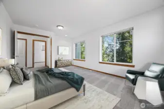 THe primary suite is very spacious and looks out toward the side yard and wooded area beyond.