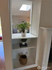 Convenient bookcase and plant shelf next to two sided fireplace