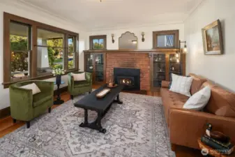 Large windows allow natural light to spill in by day, while the fire and lamps create a golden glow at night.
