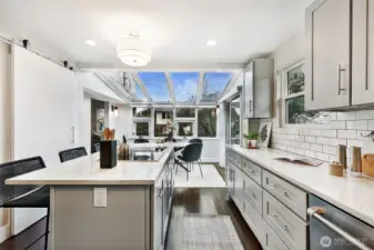 Bright, sun-filled kitchen features an oversized island, quartz countertops, custom cabinetry & generous casual dining space