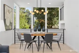 A stylish dining area enhanced by modern lighting and expansive windows showcasing lush surroundings.