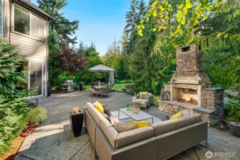 Private backyard oasis with outdoor fireplace, and paved patio, perfect for entertaining or relaxing.
