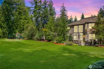 Expansive lawn framed by mature trees and manicured gardens.