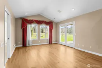 Primary bedroom with hardwood floors, vaulted ceilings and French door access to backyard and patio.