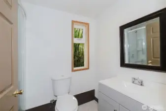 The brand-new bathroom in this studio includes a sleek rounded corner shower, new vanity, and toilet—offering fresh, modern convenience in this serene forest retreat.