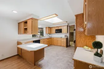 The spacious kitchen is both functional and charming, featuring generous counter space, abundant cabinets and drawers, and a built-in desk for added convenience. A garden window adds natural light, while an open, see-through cabinet connects to the dining area—perfect for displaying favorite dishes or keeping conversation flowing. The kitchen is well-equipped with a flat-top stove, brand new microwave, and double ovens, making it ideal for everyday cooking or entertaining.