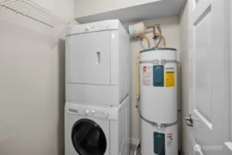 In unit laundry room with stackable washer & dryer and hot water tank.