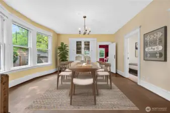 Bright dining area with tall windows overlooking the fenced side yard, plus easy flow to kitchen and bedroom. (Virtually Staged.)