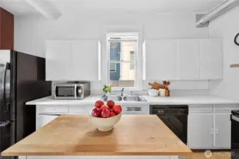 Functional kitchen with movable island, full appliance package, and window above the sink for natural light.