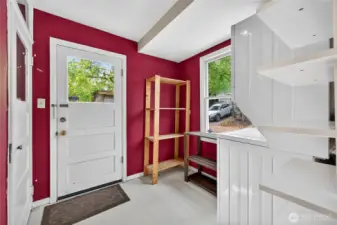 Laundry room with stacked washer/dryer, storage shelving, and natural light, featuring access to the basement and side yard.