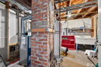 Basement utility room with hot water heating system, tool area, storage, and wash basin for practical use.