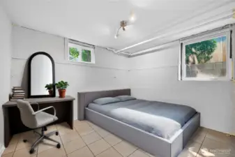 Basement bedroom with natural light, closet space, and enough room for a bed, storage, and study area. (Virtually Staged.)