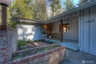 Welcoming entry with darling courtyard, brick planter box & covered porch.