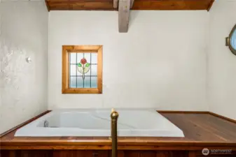 Large soaking tub with custom stain glass and working portal window