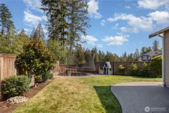 This expansive space features a covered patio with recessed lighting, fire pit, grassy area, shed, sprinkler system, and dedicated garden area.