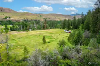 The property includes a forested hillside and a potential building site on an upper level bench for a higher outlook across the valley.
