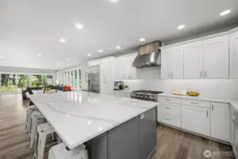 Step into a gourmet chef's haven featuring premium GE Monogram appliances, complemented by an oversized quartz island that offers both casual dining space and abundant storage.