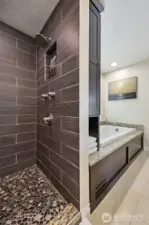 This walk in shower has a rain shower head, a separate shower wand, & pebble tile that feel amazing on your feet!