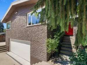 Home's elevation showcases mid-century modern architectural touches, brick with weeping mortar & cedar wood