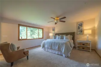 Primary bedroom on upper level with serene views of the backyard and woods.