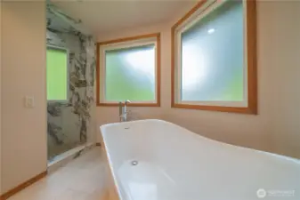 Luxurious primary bathroom with standalone tub and shower with rain head and more.