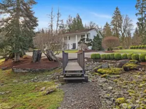 Beautifully landscaped grounds with mature trees, stone accents, and a private setting that enhances the outdoor experience.