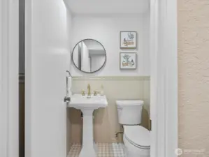 Updated main floor powder room with pedestal sink, modern fixtures, and classic wainscoting detail.