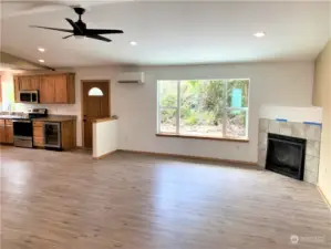 Look from entrance into Living room with fireplace, ceiling fan, large kitchen on the left