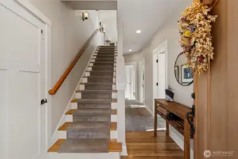 Front entry. Elevator to the left, and guest bed, bath/laundry, and primary suite to the right. Stairs lead to living, dining, and kitchen.