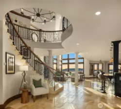 Upon entering the home, a grand foyer opens beneath soaring two story ceilings, immediately creating a breathtaking sense of scale and elegance. A magnificent staircase commands attention as it gracefully takes your eye up to the custom chandelier powered with a lowering system for cleaning.