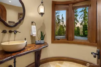 A one-of-a-kind Turret bathroom featuring custom wall fixtures, a Crotch cut African Mahogany countertop and hand-crafted tree support.