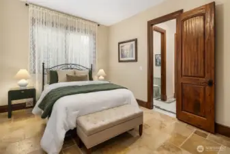 Downstairs guest bedroom with continued travertine flooring and private bath.