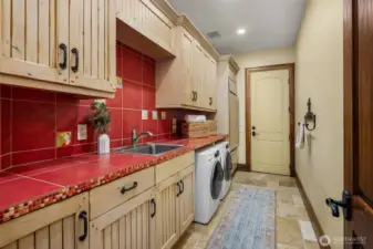 A dreamy laundry room complete with custom built-in cabinets, tile countertops and backsplash, utility sink and a second built-in Sub-Zero refrigerator.