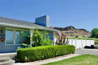 close up of ranch house showing mature managed landscaping and house in great shape with desert topography in the background