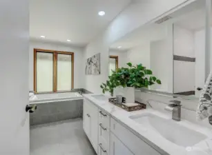Beautifully remodeled bath with dual sink granite top vanity and sunken tub and heated tile floor.