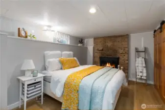 Cozy lower-level spare room featuring a warm wood-burning fireplace, perfect for guests or relaxation.