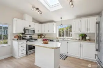 Kitchen with island, stainless steel appliances, and skylight.