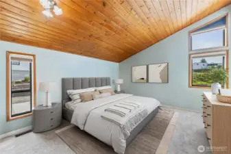 Spacious primary with a walk-in closet and vaulted wood ceilings.