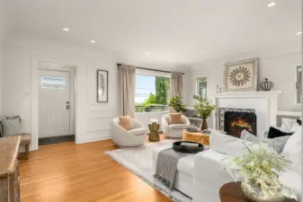 Spacious living room with oversized windows, hardwood floors, gas fireplace & custom built shelving